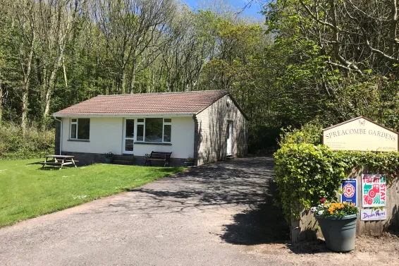 An exterior view of Azalea Cottage and the entrance sign at Spreacombe Holiday Cottages
