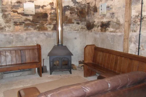 The seating area with wood burner inside The Barn at Spreacombe Holiday Cottages
