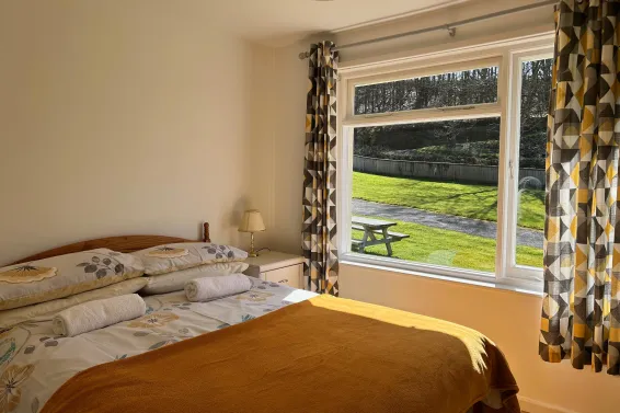 A double bedroom inside Hibiscus Cottage with views over the lawns at Spreacombe Holiday Cottages