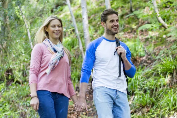 A couple enjoying walking their dog through woodlands enjoying a peaceful break