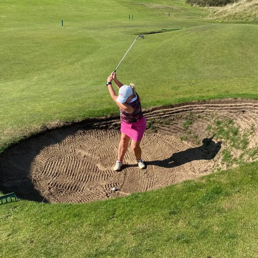 Lady golfer hitting out of a deep bunker , Saunton