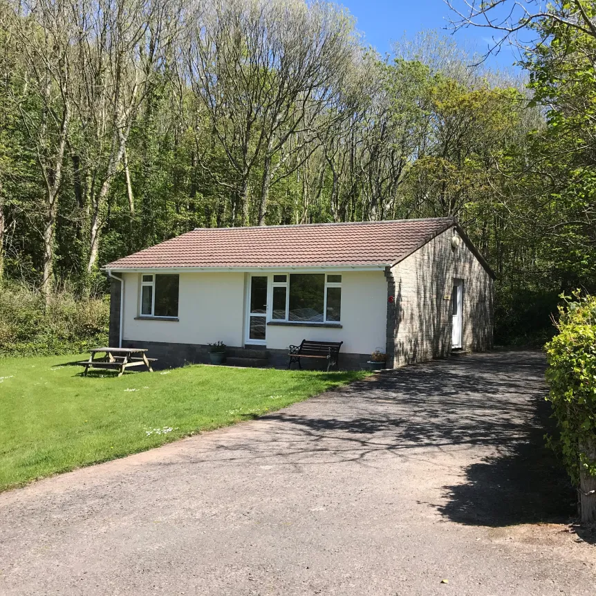 An exterior view of Azalea Cottage and the entrance sign at Spreacombe Holiday Cottages