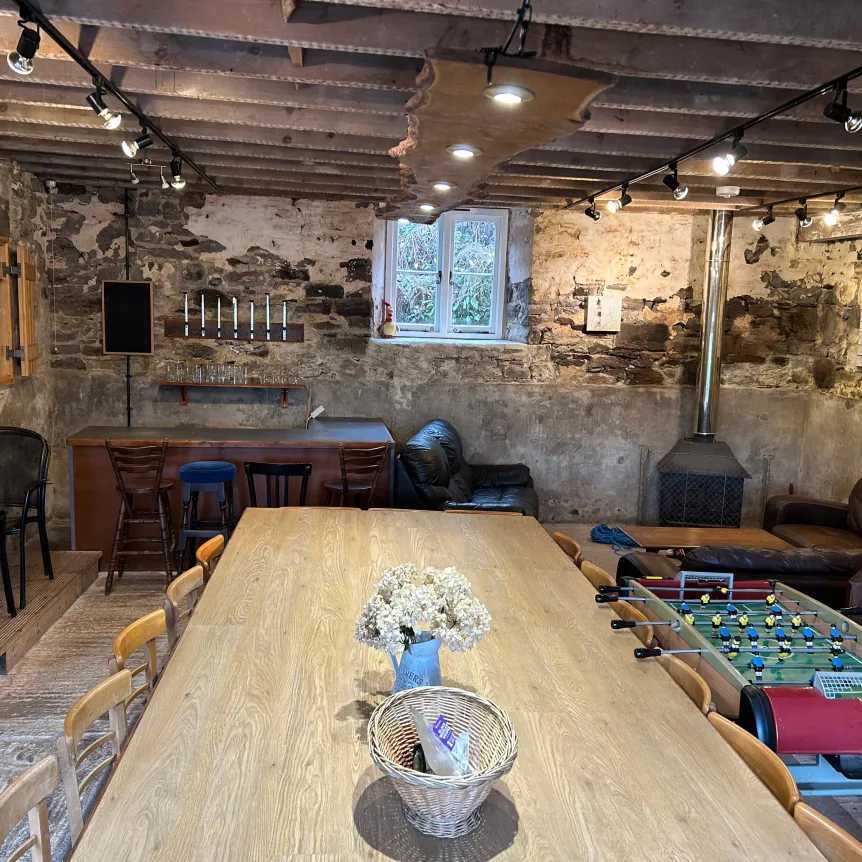 A view into The Barn at Spreacombe Holiday Cottages with a large table and seating area with wood burner