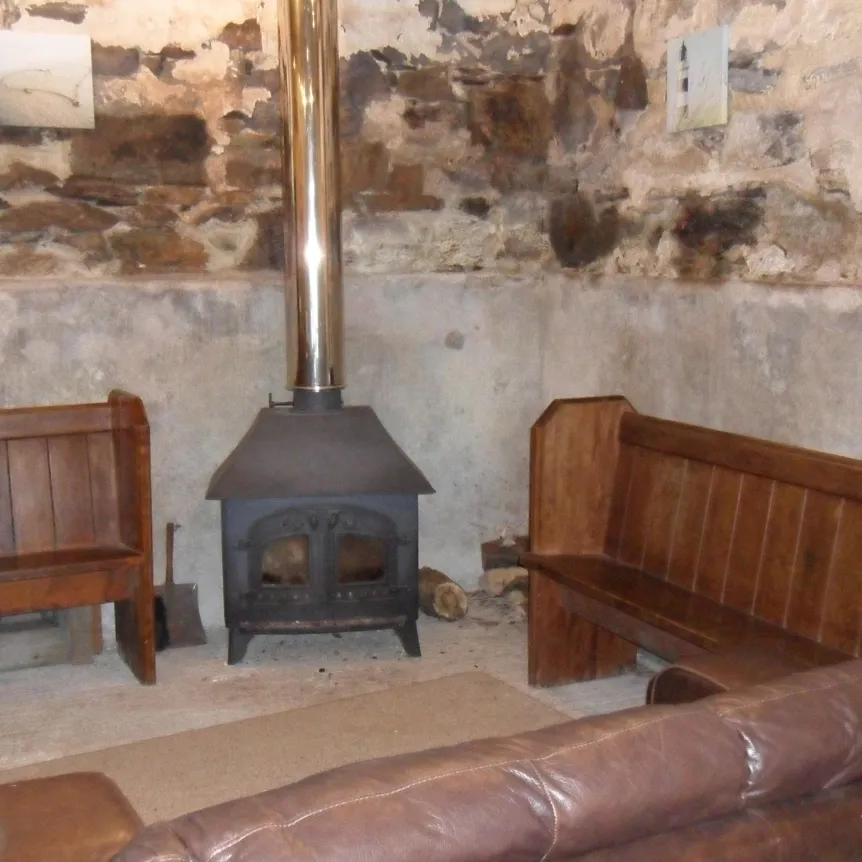 The seating area with wood burner inside The Barn at Spreacombe Holiday Cottages