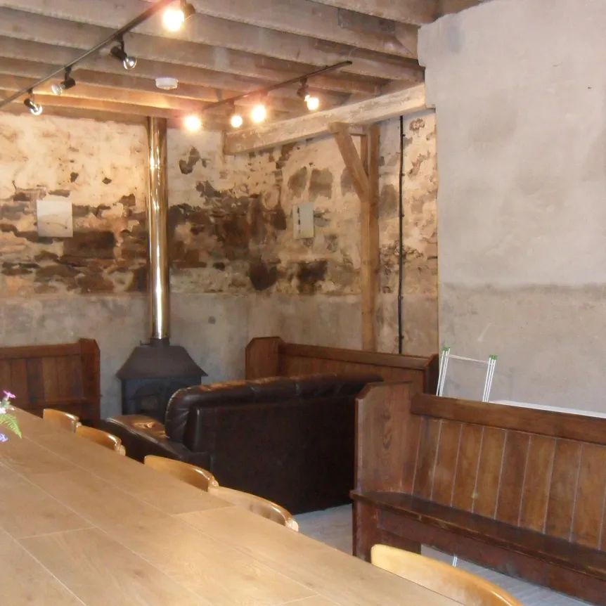 Seating, a table and a wood burner in The Barn at Spreacombe Holiday Cottages