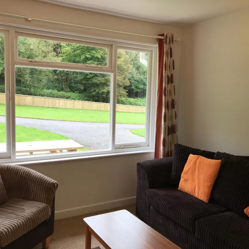 Sofa and chairs in the lounge of Begonia Cottage with a view over the lawns at Spreacombe Holiday Cottages