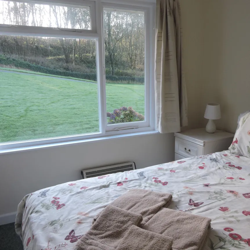 A double bedroom inside Camellia Cottage with a view over the lawns at Spreacombe Holiday Cottages