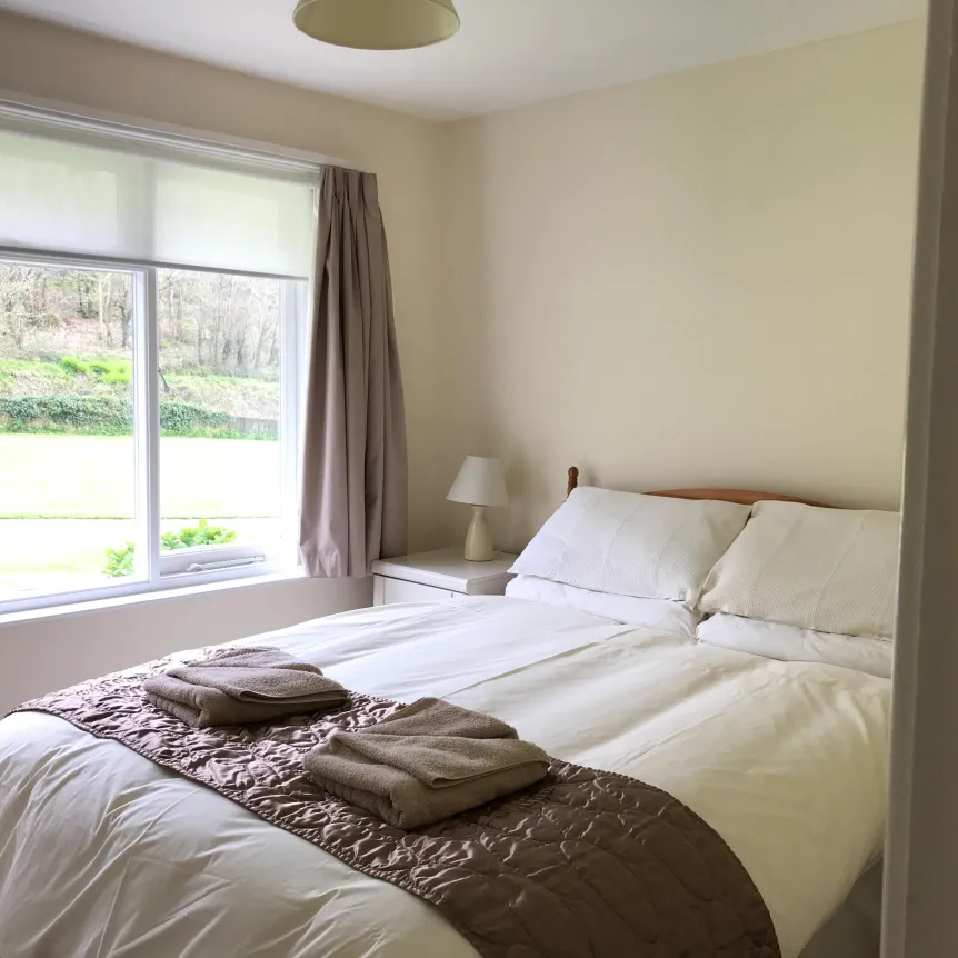 A double bedroom inside Camellia Cottage with a view over the lawns at Spreacombe Holiday Cottages