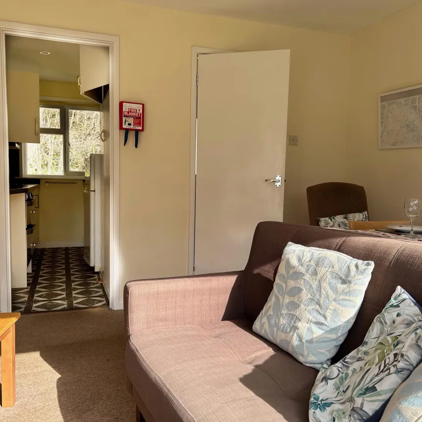 The lounge area and view into the kitchen inside Camellia Cottage at Spreacome Holiday Cottages
