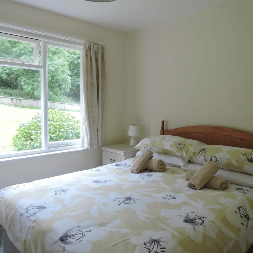 The double bedroom inside Clematis Cottage with a view over the lawns at Spreacombe Holiday Cottages