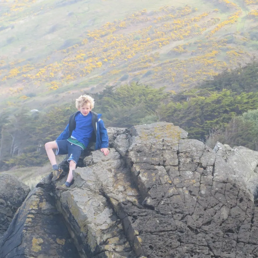 A young boy climbing over rocks in the countryside
