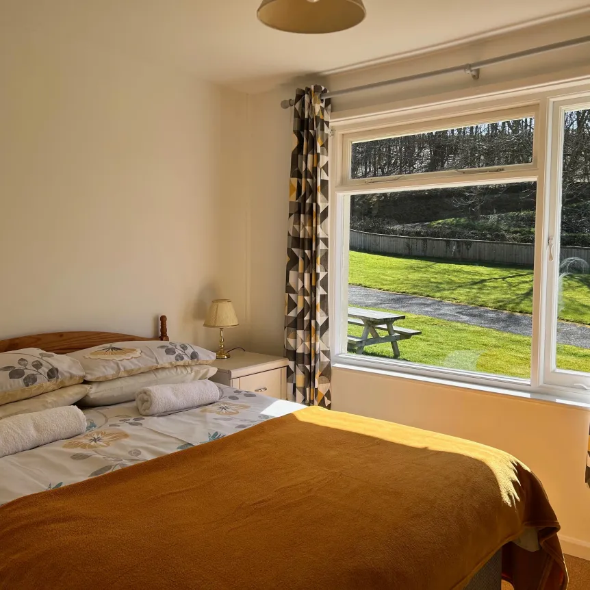 A double bedroom inside Hibiscus Cottage with views over the lawns at Spreacombe Holiday Cottages