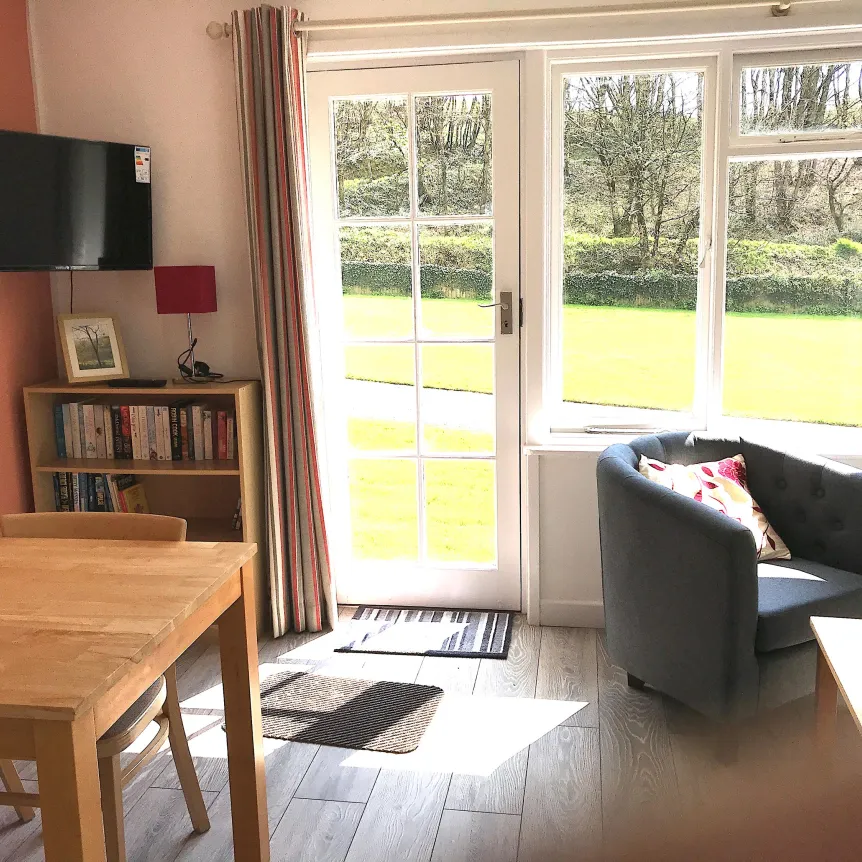 The lounge diner inside Hibiscus Cottage with a view of the lawns at Spreacombe Holiday Cottages