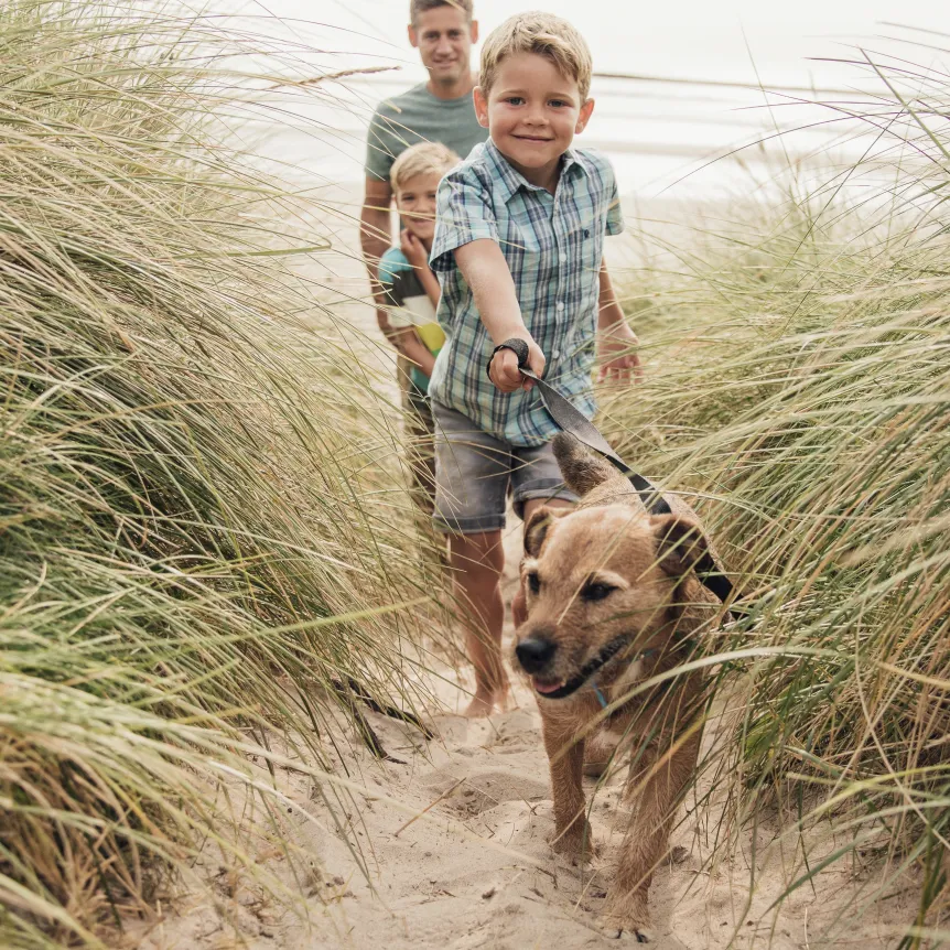Family walking a dog in on the beach whilst on holiday in North Devon