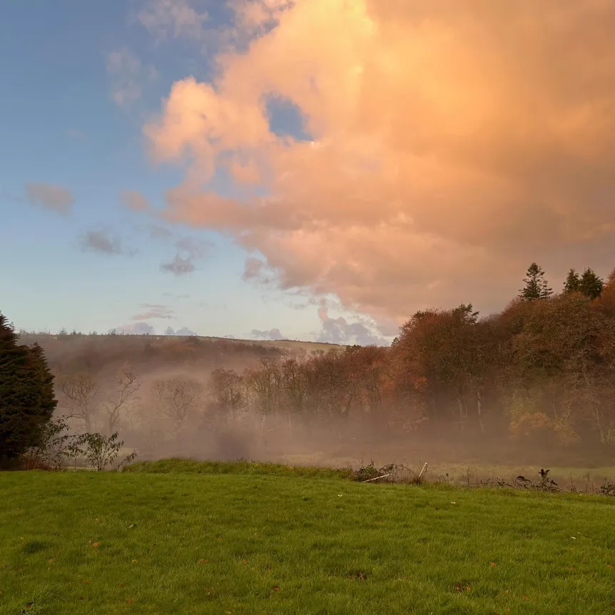 A sunset over fields and woodland