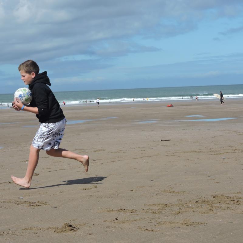 boy playing rugby on the beach