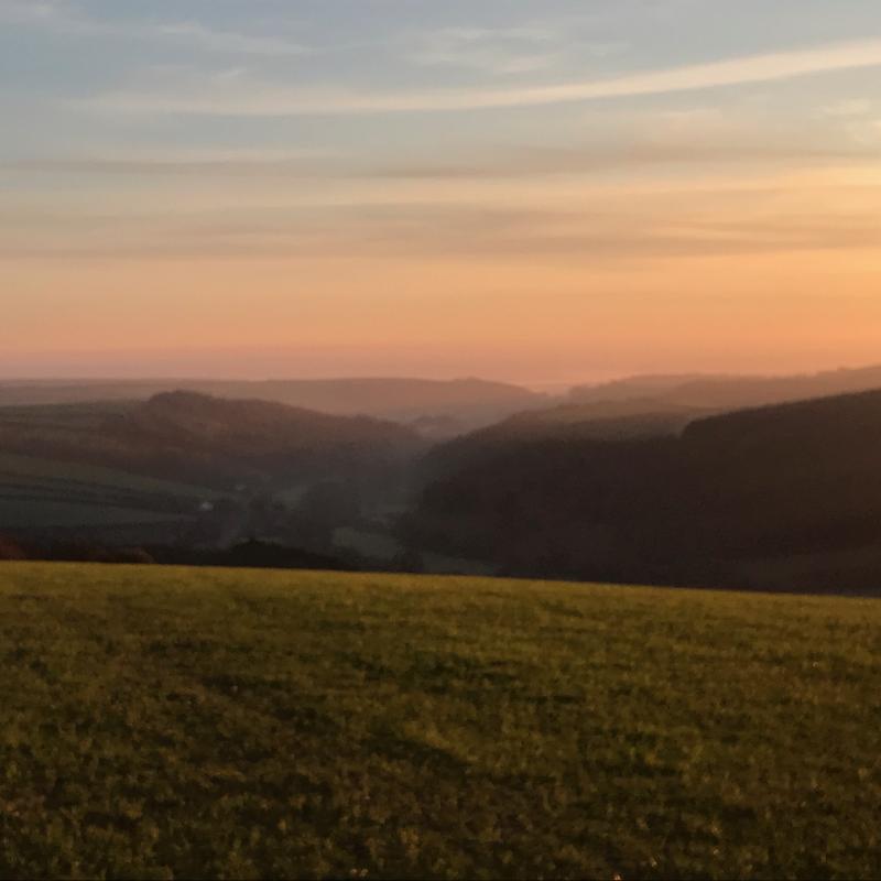 The sun setting over the fields from the top of a hill in North Devon