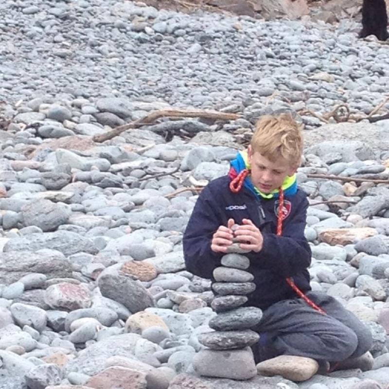 Young boy making a rock sculpture at Heddon's Mouth